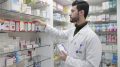 Apotheker nimmt Medikament aus dem Regal