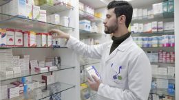 Apotheker nimmt Medikament aus dem Regal