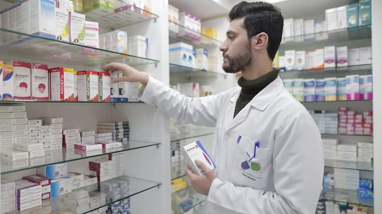 Apotheker nimmt Medikament aus dem Regal